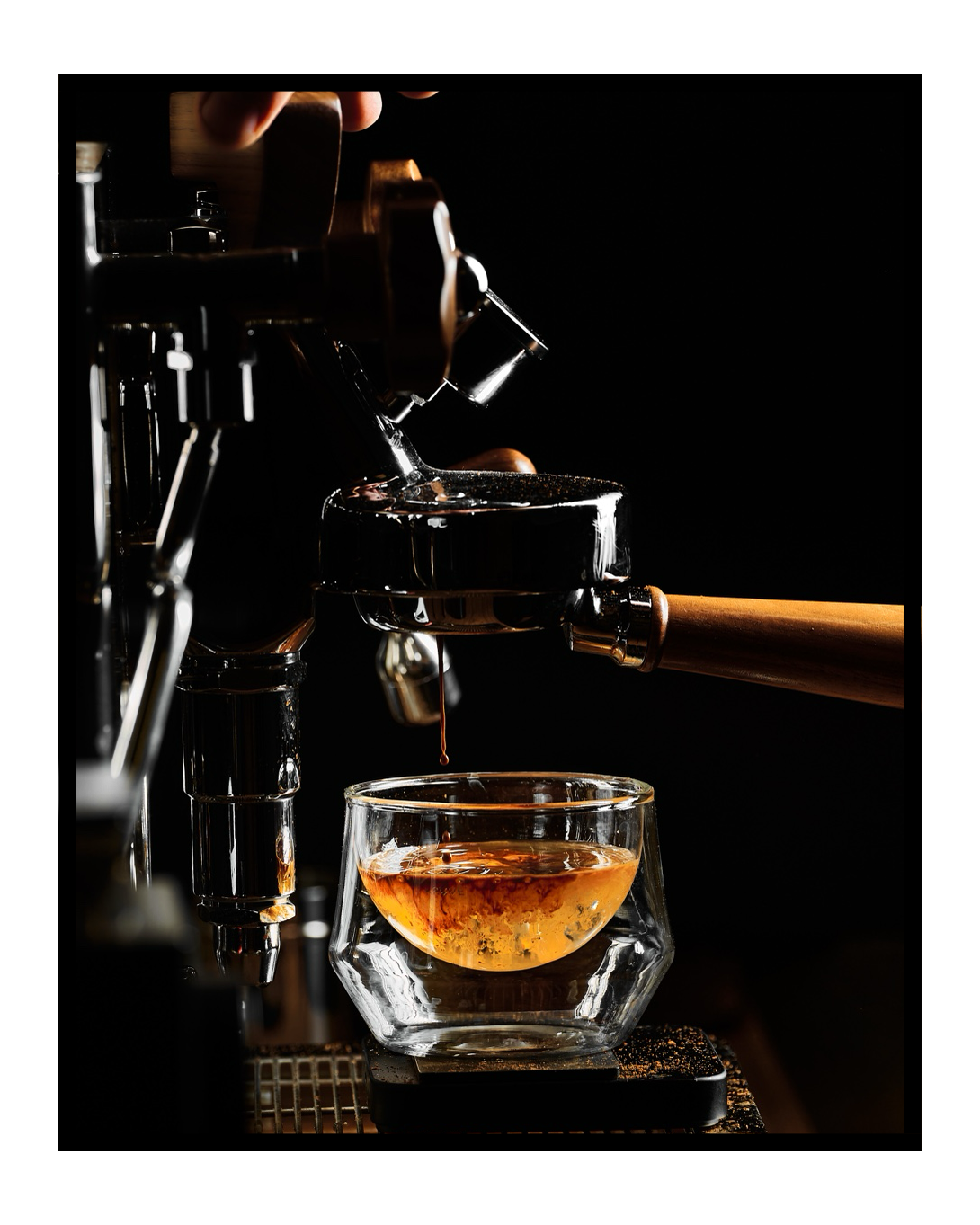 An espresso being prepared, framed with a black border on white