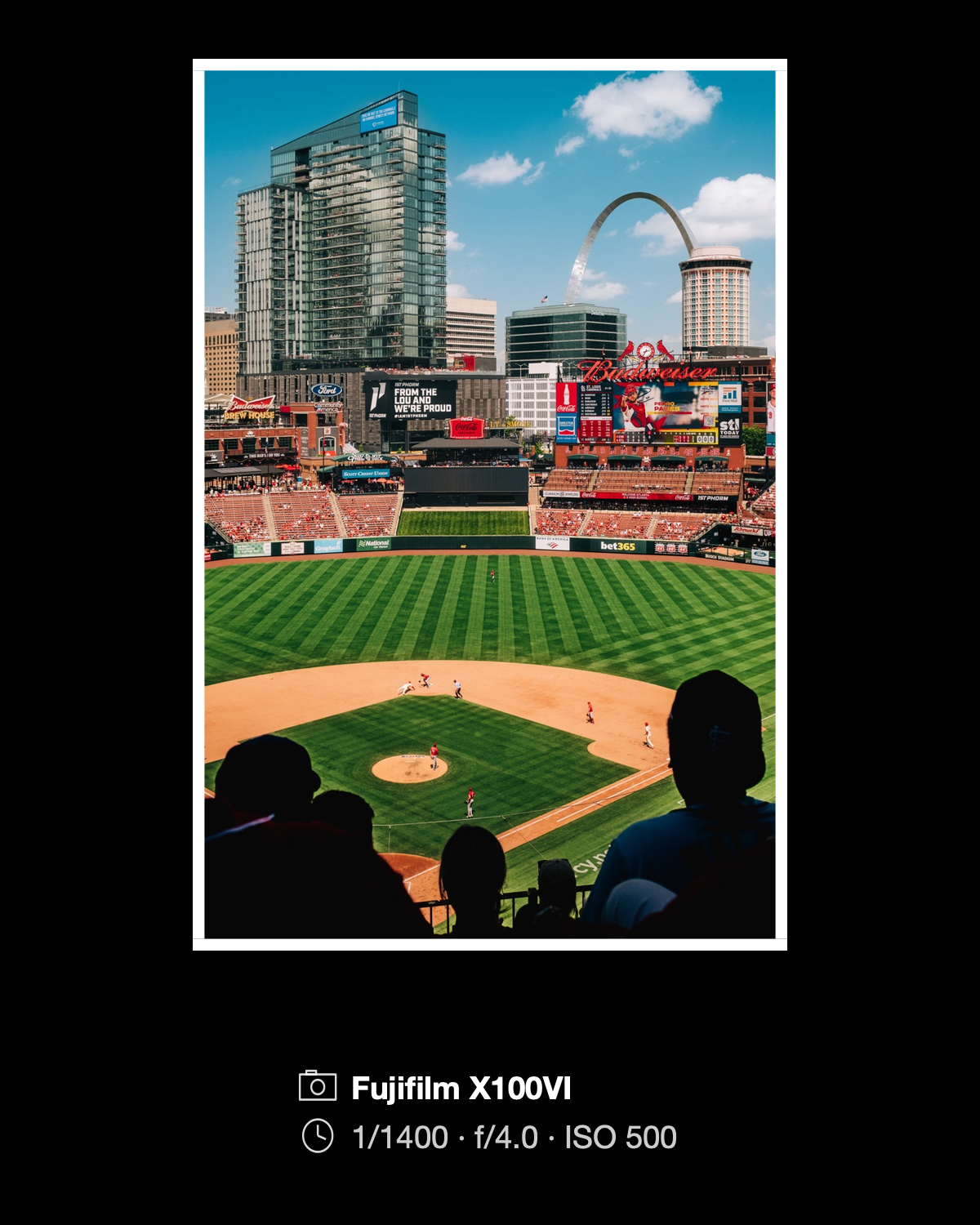 A baseball game framed in white on black with its Fujifilm X100VI camera and exposure details below